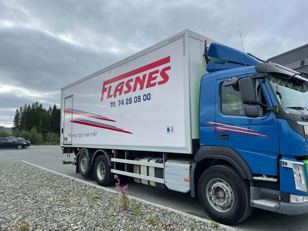 Blå lastebil med logo for Flasnes.