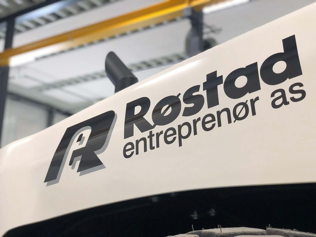 Hvit traktor med logo for Røstad Entreprenør AS.