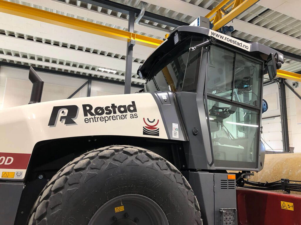 Hvit traktor med logo for Røstad Entreprenør AS.